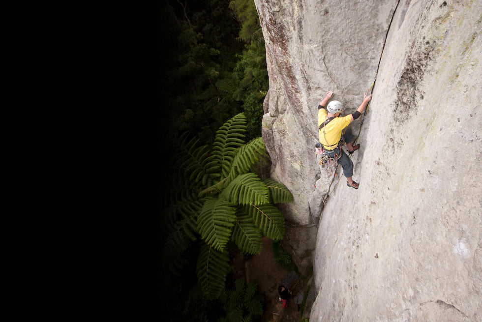 Bryce Martin climbs the ignimbrite crack classic Millennium Madness above tree ferns at Waipapa, photo Marten Blumen.